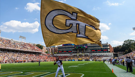 A college student waves a flag with the Georgia Tech logo in one of the endzones at Bobby Dodd Stadium.